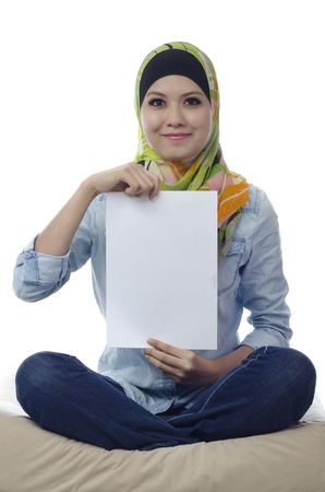 Beautiful young muslim woman seat and holding a blank paperの写真素材