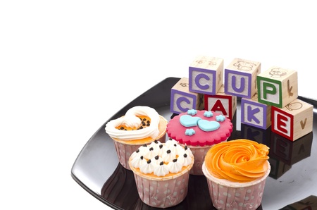 Close up colorfull cup cakes with wood blocks on black plateの写真素材