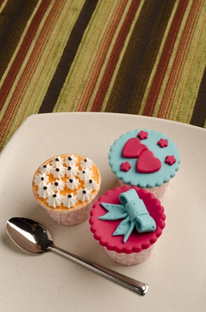 Colorfull cup cakes with spoon  on white plate isolate stripe backgroundの写真素材