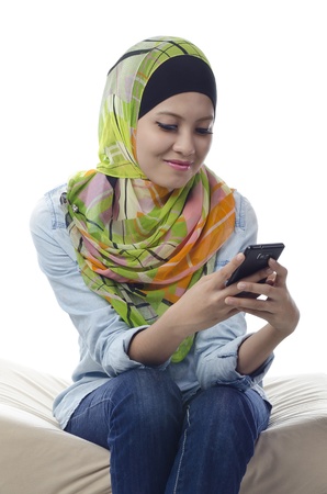 beautiful young muslim woman with colorful head scarf sending text messagingの写真素材