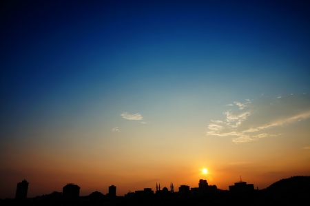 silhouette of urban skyline isolated on orange sunset and blue sky viewの写真素材