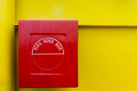 Red fire hose box with yellow background.