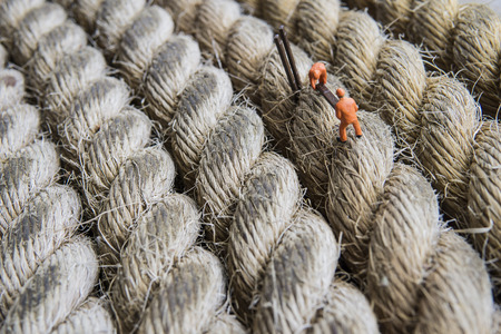 Miniature figure working in industrial - Close up of construction workers teamwork concept on rope surface with selective focus.の写真素材
