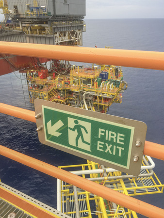 Emergency Escape Route. Fire exit signage display on handrail nearby stairs at oil and gas platform.の写真素材
