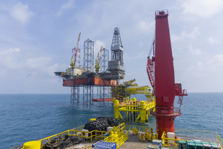 Oil and gas industry. View of jack up rig with Accommodation Work Barge (AWB) and unfinished oil and...