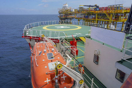 Oil and gas industry. View of commercial diving vessel nearby oil and gas drilling platform in open sea.の写真素材