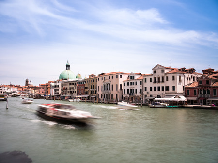 A view from close to Ferrovia in Venice, Italy along the main channel. You see boats pass by and the San Simeone Piccolo church a bit further away. To the left you see the Ponte degli Scalzi bridge. No people or brands are visible to its safe for commerciの写真素材
