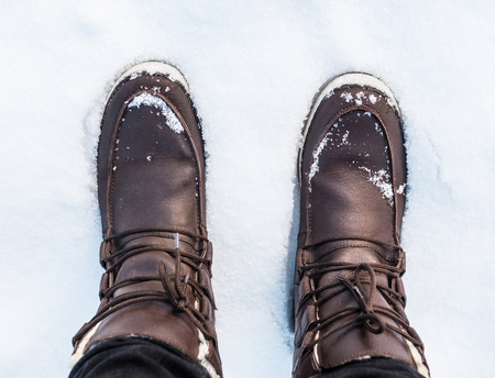Brown winter boots in the white snow, looking down from a first person perspective. Location: Sweden.の写真素材