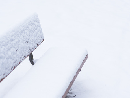 A lonely park bench is covered in snow. Location: Sweden.の写真素材