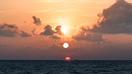 A beautiful sunrise with three suns in different stages - multiple exposure. Location: Thailand.の写真素材