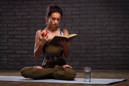 Beautiful Girl Doing Yoga Exercises And Read Book On Brick Wall Backgroundの写真素材