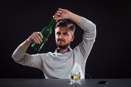 Frustrated Man Opens A Bottle On Black Background
