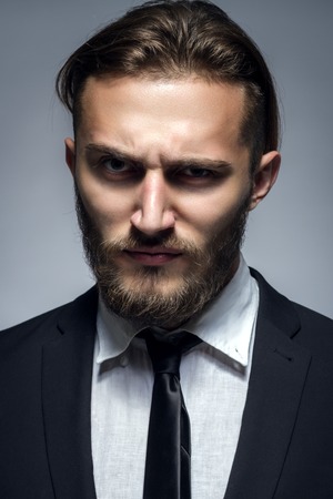 Handsome Man With Beard In Black Suit On Gray Backgroundの写真素材