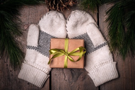 Christmass Gift Box And Mittens On Wooden Table Near Tree Branchesの写真素材