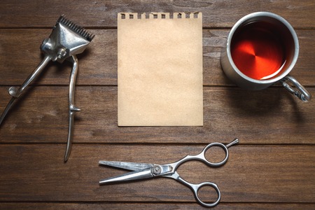 Old Vintage Manual Metal Hair Clipper, Scissors, Paper And Cup On Wooden Tableの写真素材