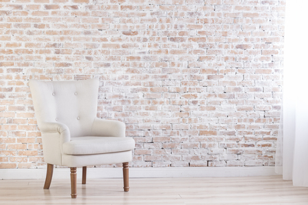 White Armchair On Brick Wall Background Near Window