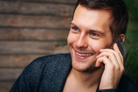 Portrait Of A Smiling Handsome Man In Suit With Smartphone On Wooden Backgroundの写真素材