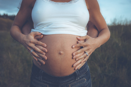 Couple with hands on the womans pregnant belly.の写真素材
