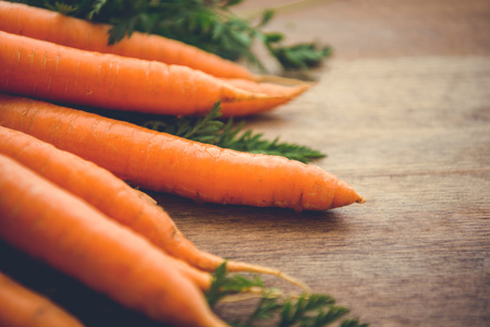 Carrots with green on a wooden rustically board.