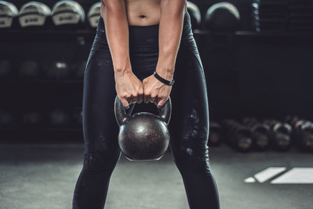 Woman in gym holding a kettlebell. Working Out at Crossfit.の写真素材
