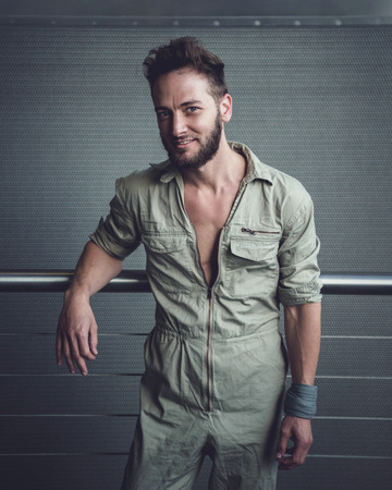 Handsome man in mid thirties wearing a khaki one piece jumpsuit posing.の写真素材