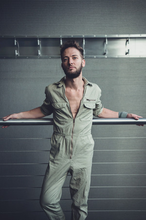 Handsome man in mid thirties wearing a khaki one piece jumpsuit posing.の写真素材