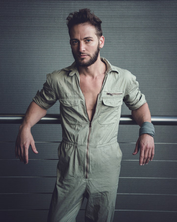 Handsome man in mid thirties wearing a khaki one piece of jumpsuit posing.の写真素材