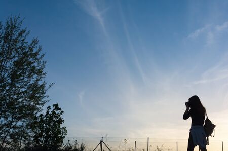 backlit silhouette of a photographer at sunsetの写真素材