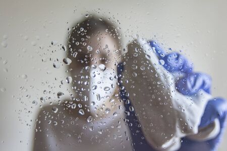 caucasian woman cleaning and disinfecting a glass with a cloth and spray in Spainの写真素材