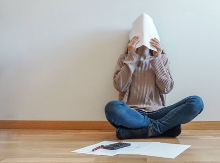 frustrated young woman reviewing documents, covering her face with the papersの写真素材