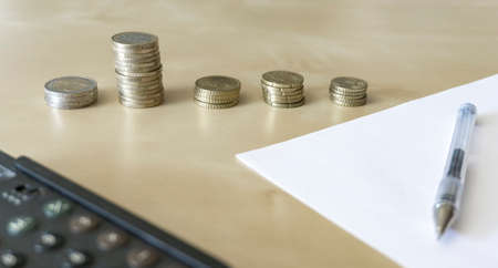 stack of coins, calculator and paper on wooden tableの写真素材