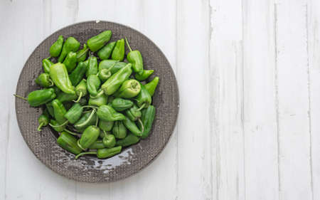 padrÃ³n peppers in a dark ceramic plate on white wooden background