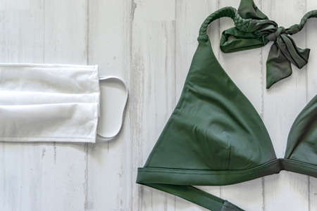 green bikini and surgical mask to protect yourself in the pool or beach on vacationの写真素材