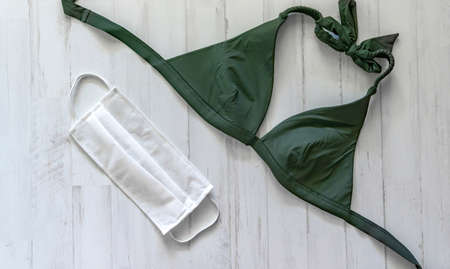 green bikini and surgical mask to protect yourself in the pool or beach on vacationの写真素材