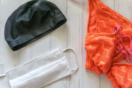 orange bikini, black swimming cap and surgical mask to protect yourself in the pool or beach on vacationの写真素材