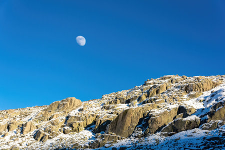 Nice view of the moon over the rocks of a snowy mountain in Avila, Spainの写真素材