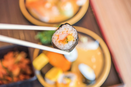Sushi roll : Roll sushi held by chopsticks from background of assorted sushi setの写真素材