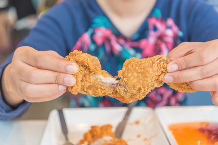 Hand holding Fried chicken and eating in the restaurantの写真素材