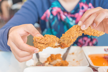 Hand holding Fried chicken and eating in the restaurantの写真素材
