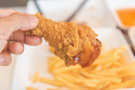 Hand holding Fried chicken and eating in the restaurantの写真素材