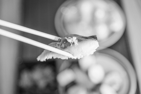 picking up a piece of sushi with chopsticks , black and whiteの写真素材