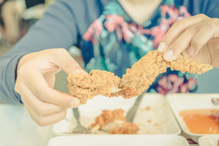 Hand holding Fried chicken and eating in the restaurant ,vintageの写真素材