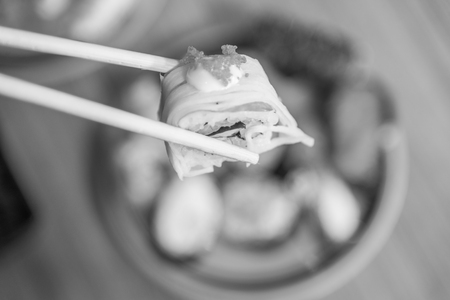 Sushi roll : Roll sushi held by chopsticks from background of assorted sushi set , black and whiteの写真素材