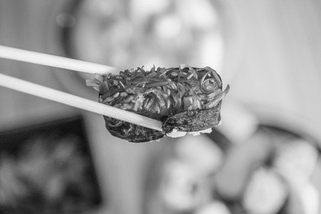 picking up a piece of sushi with chopsticks , black and whiteの写真素材