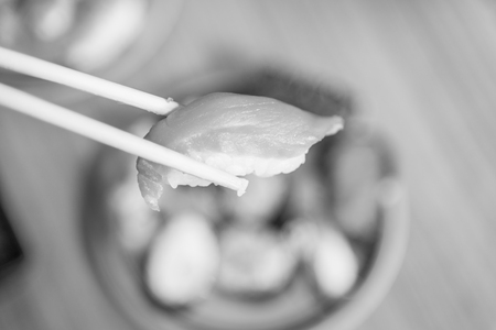 picking up a piece of sushi with chopsticks , black and whiteの写真素材