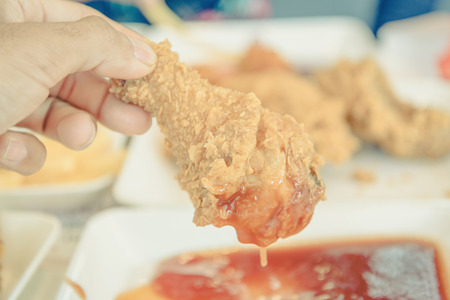 Hand holding Fried chicken and eating in the restaurant ,vintageの写真素材