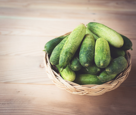 Fresh cucumbers in basket on wood , vintage toneの写真素材