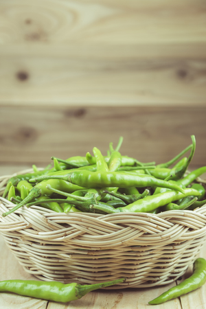 Green peppers in wicker basket on wooden background , vintage toneの写真素材