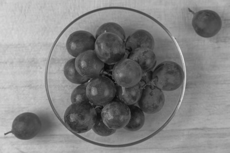purple round grapes on old wooden table , black and whiteの写真素材