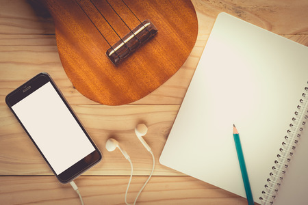 Ukulele guitar with earphone on wooden table , vintage toneの写真素材